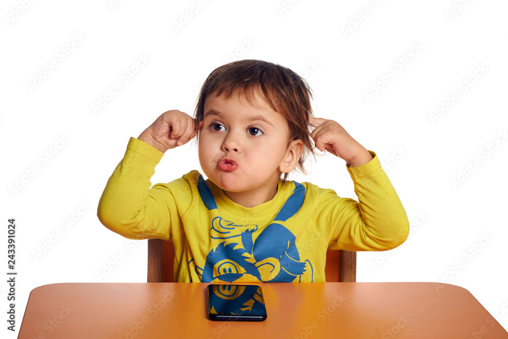 Adorable little child using phone at desk, isolated on white background, shot in studio Adorable little child using phone at desk, isolated on white background, shot in studio