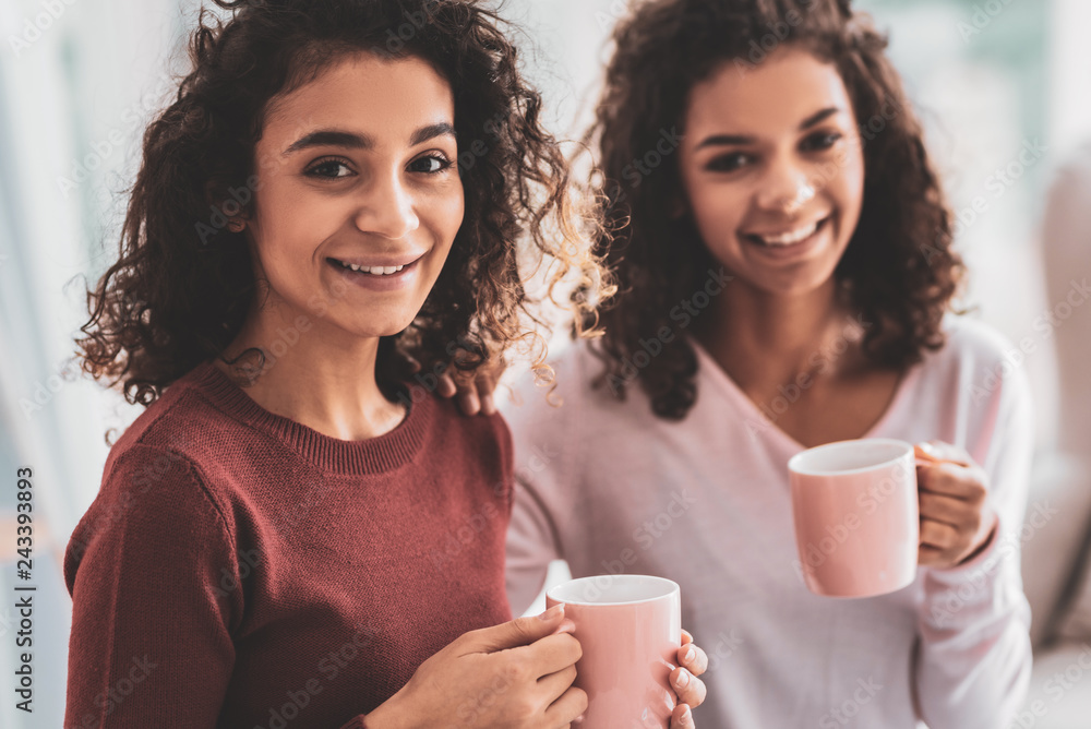 Beaming sisters drinking hot cocoa on cold winter evening Beaming sisters drinking hot cocoa on cold winter evening