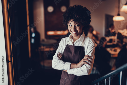 Attractive employee standing in cafe and looking at camera