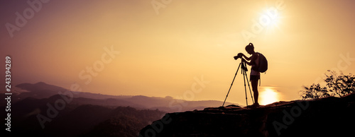 woman photographer taking photo on sunset mountain peak photo