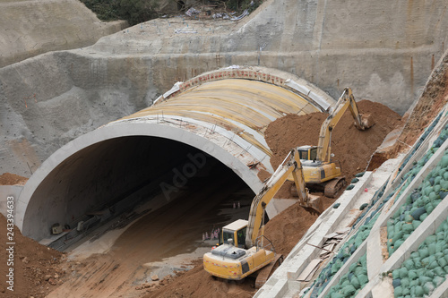 Highway tunnel construction site with yellow tractors