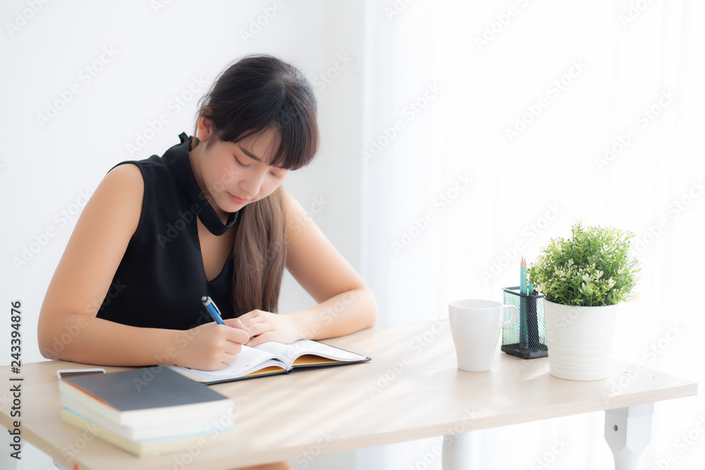 Beautiful young asian woman smiling sitting study and learning writing notebook and diary in the living room at home, girl homework, business woman working on table, education concept. Beautiful young asian woman smiling sitting study and learning writing notebook and diary in the living room at home, girl homework, business woman working on table, education concept.