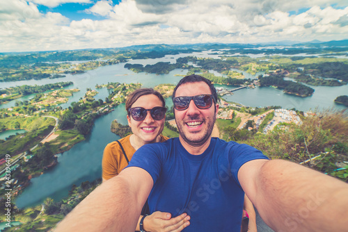 happy tourist take selfie photo in Guatape, landscape of the lake of Guatape from Rock of Guatape (Piedra Del Penol) in Medellin region, Colombia 