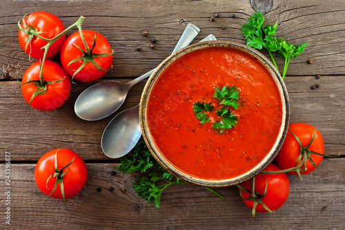 Homemade tomato soup. Top view, table scene with ingredients on a rustic wood background.