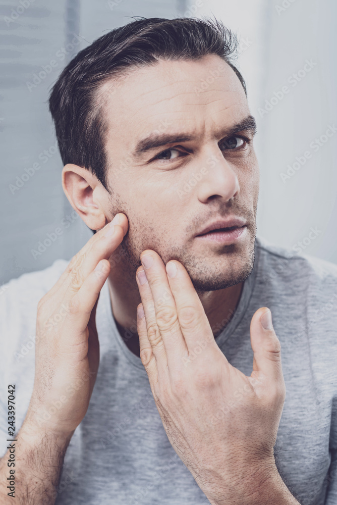 Handsome male person examining his face Handsome male person examining his face
