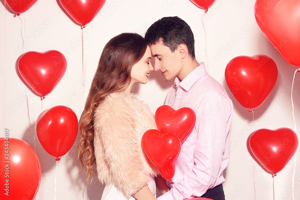 Man with his lovely sweetheart girl kiss at Lover's valentine day.  Valentine Couple. Couple kiss and hug. On background red balloons hearts.  Love concept. Happy smile girl. Lovers touch foreheads Photos