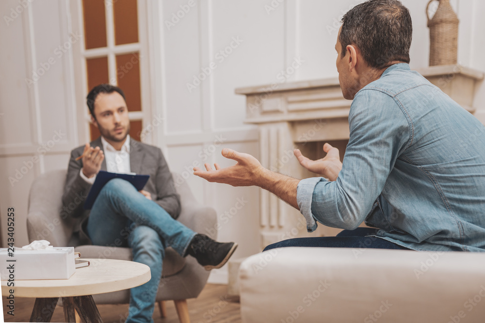 Fototapeta premium Mature man feeling curious while talking to psychologist