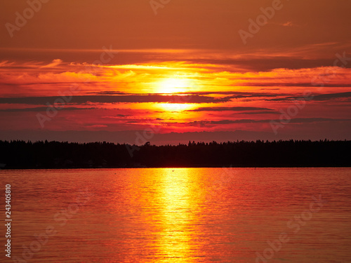 Red sunset sky with the sun and colorful clouds