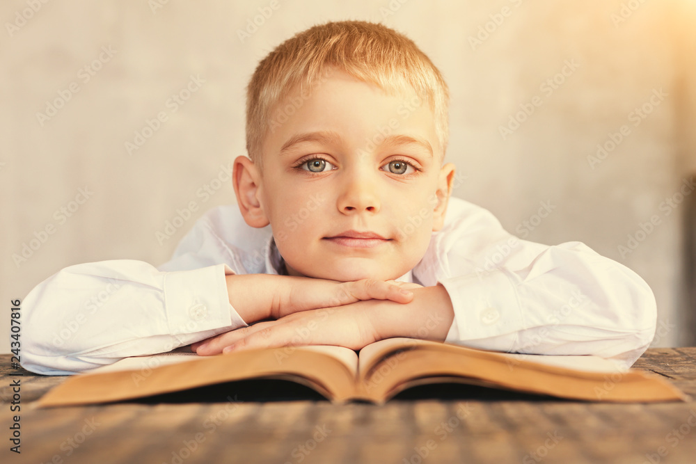 Pleasant boy resting chin on arms folded on book Pleasant boy resting chin on arms folded on book