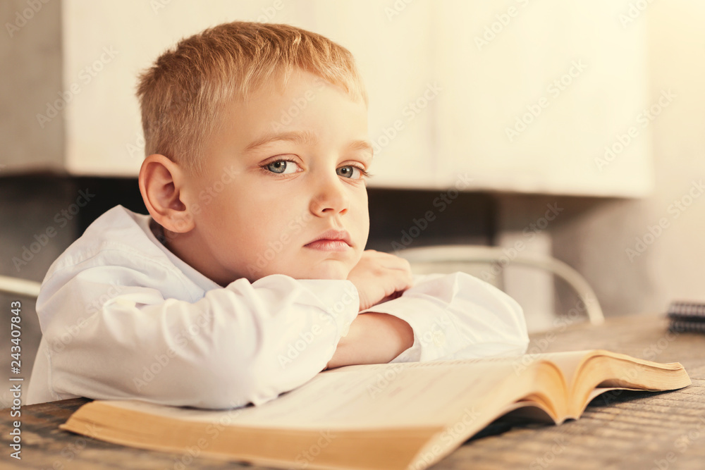 Sad boy being tired of reading a book