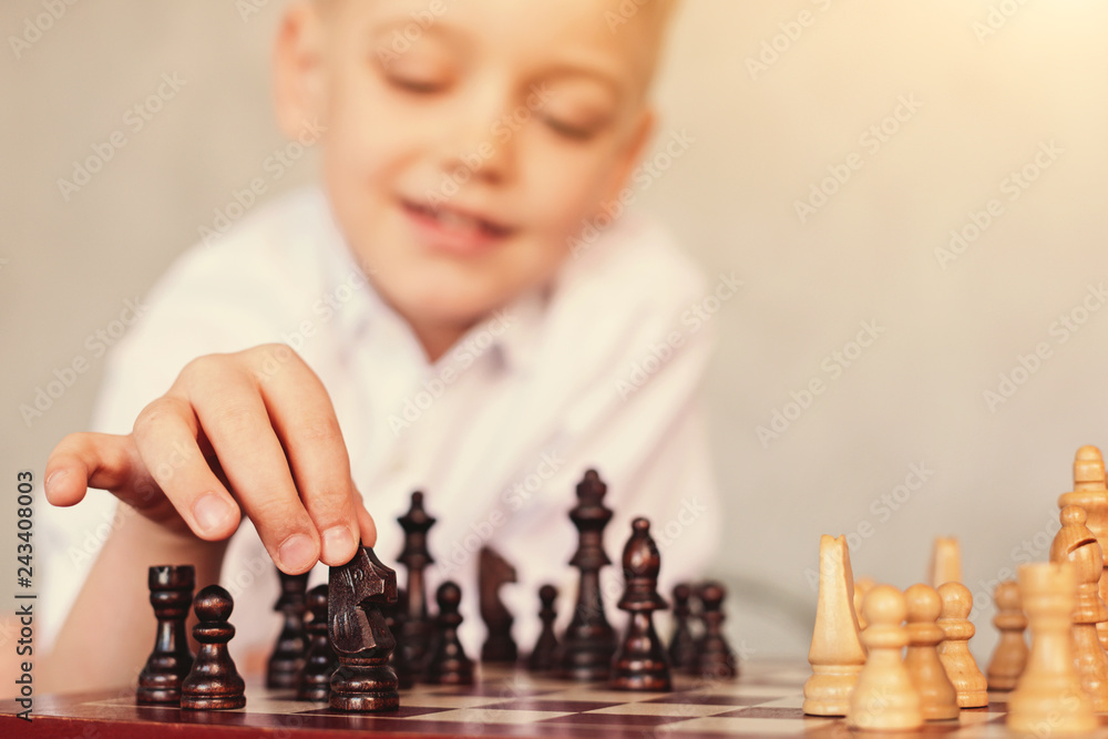Little boy moving knight across chessboard - obrazy, fototapety, plakaty 