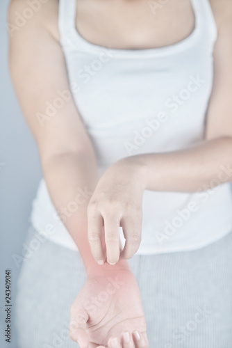 Woman scratching hand from itching on white background. Cause of itchy skin include insect bites  dermatitis  food drugs allergies or dry skin. Concept of health care skin.