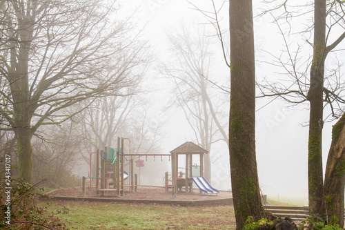 Playground equipment is unused on a damp and foggy morning; fog surrounds a playground on a day too cold for children to play photo