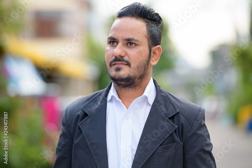 Face of bearded Indian businessman thinking outdoors