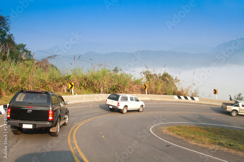 driving on curve road in the mountain with the sea mist and blue sky and forest, country road in north of Thailand © Phatthaya