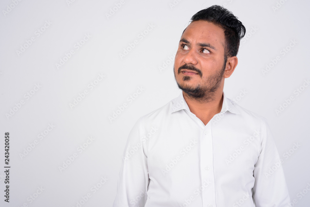 Studio shot of bearded Indian businessman thinking and looking up Studio shot of bearded Indian businessman thinking and looking up
