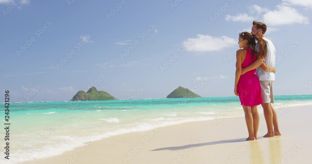 Couple on beach vacation summer holidays relaxing. Young happy people standing from behind embracing in love looking at the ocean on beach. RED EPIC SLOW MOTION. Couple on beach vacation summer holidays relaxing. Young happy people standing from behind embracing in love looking at the ocean on beach. RED EPIC SLOW MOTION.