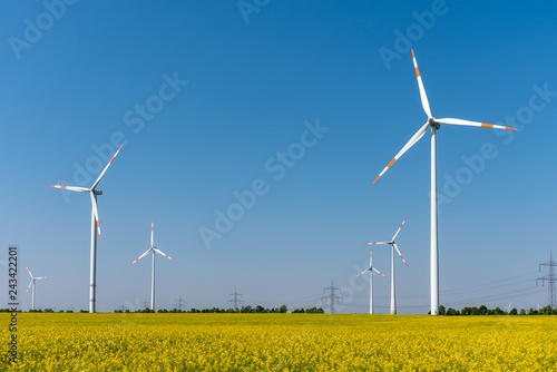 Modern wind turbines and flowering oilseed rape seen in Germany
