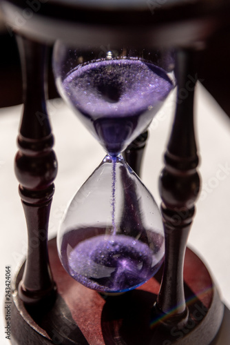 Closed up of sandglass or hourglass with violet, purple sand