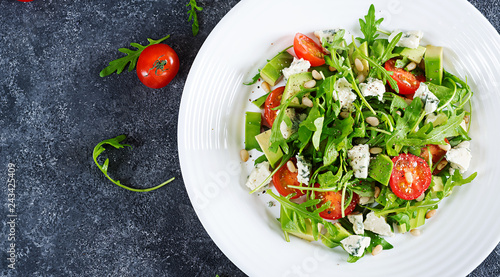 Dietary salad with tomatoes, blue cheese, avocado, arugula and pine nuts. Top view. Flat lay.