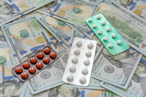 Pills on 100 dollar money. Medicine expenses. High costs of expensive medication concept