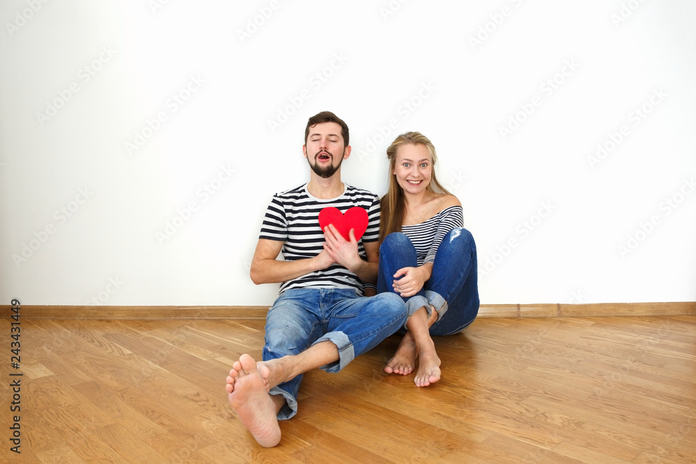 Happy valentines couple sitting on a wooden floor. White background copy space. Happy valentines couple sitting on a wooden floor. White background copy space.