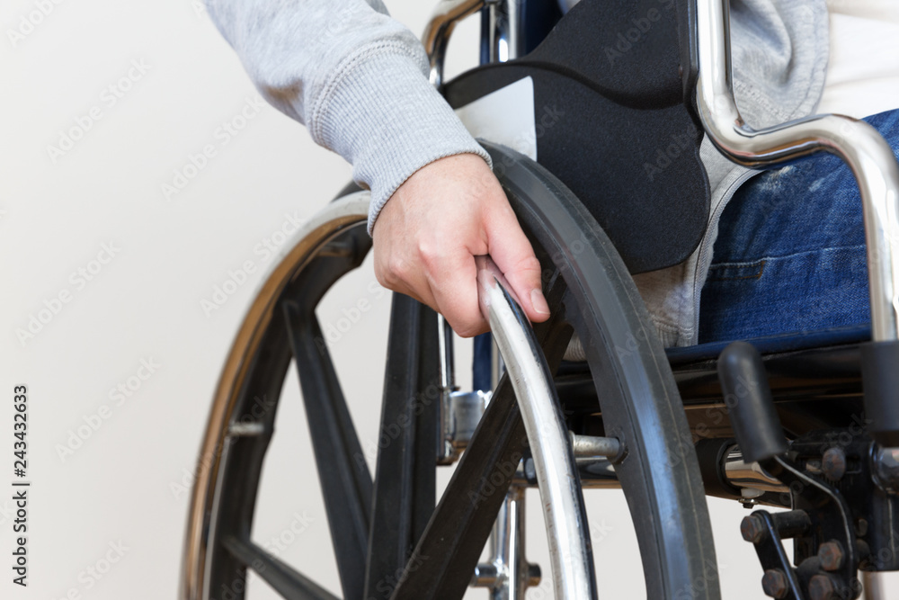 Obraz premium Detail of disabled woman holding a hand on wheel of a wheelchair.