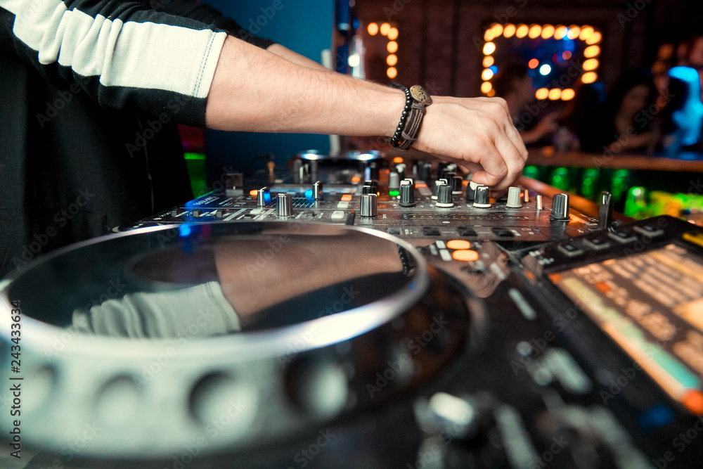 control DJ for mixing music with blurred people dancing at party in nightclub control DJ for mixing music with blurred people dancing at party in nightclub