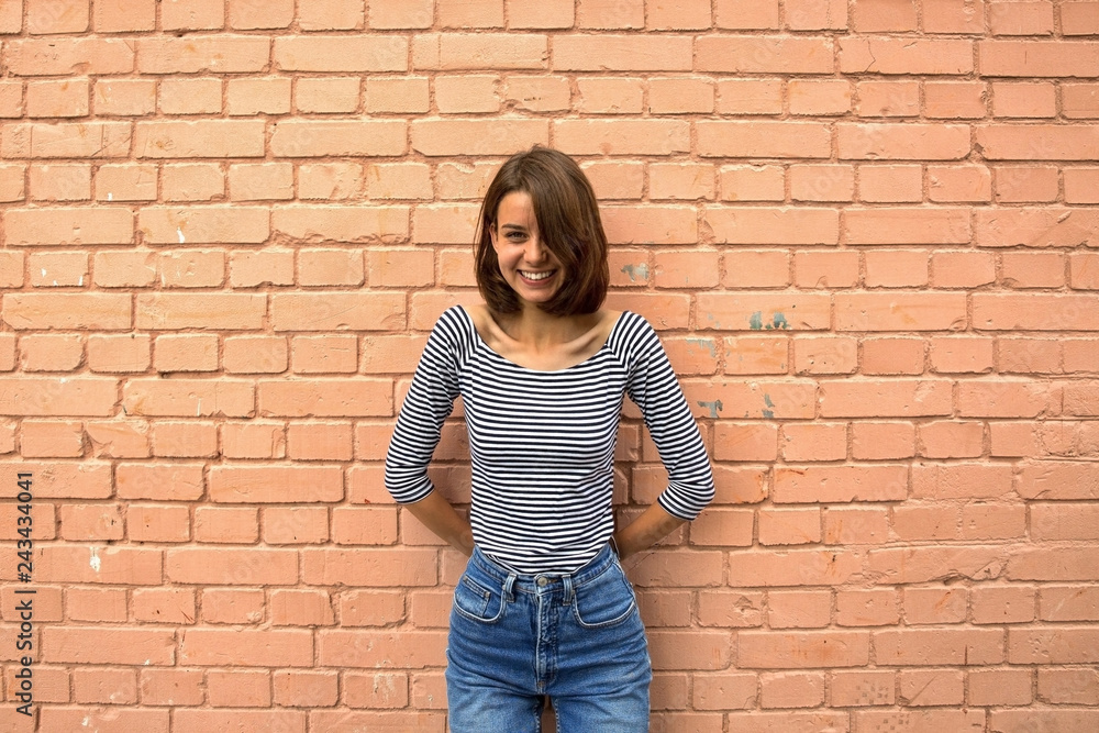 The girl is happy and smiling against the brick wall. Copy space, close up. The girl is happy and smiling against the brick wall. Copy space, close up.
