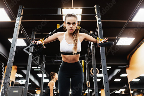Bottom view - a spectacular young brunette girl is engaged in the gym for building muscles and a beautiful figure. The concept of professional sports and taut body