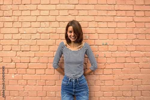 Fotografie The girl is happy and smiling against the brick wall