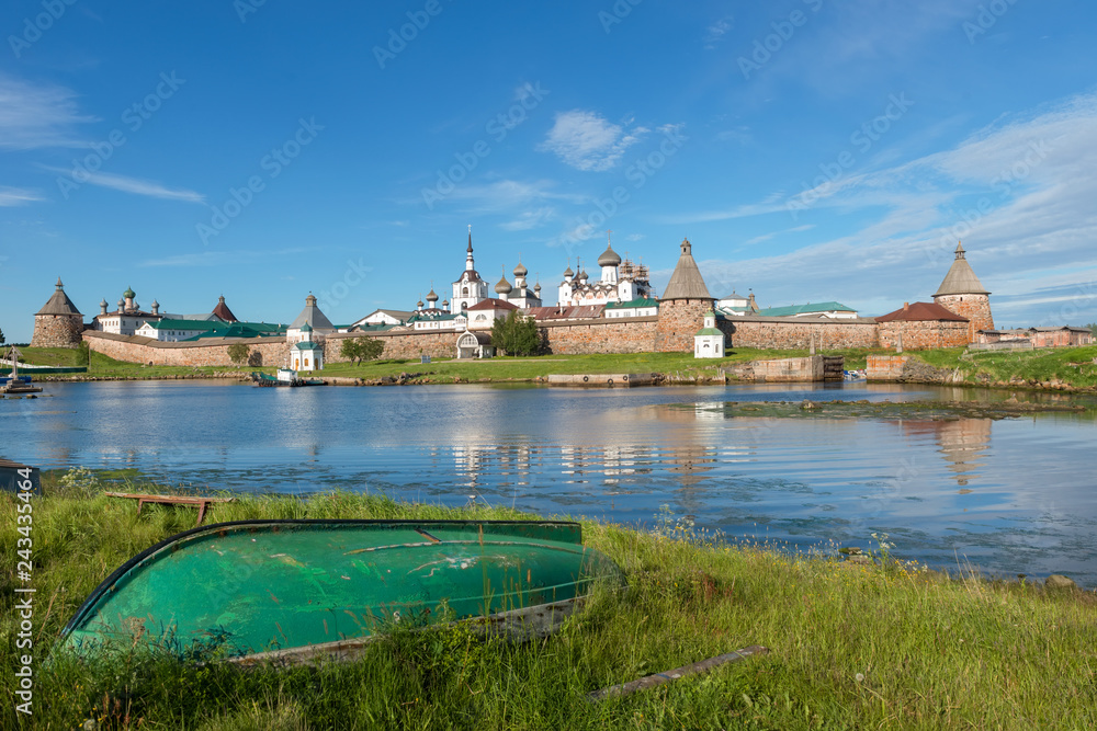 Old fishing boats on the shore against the background of the Transfiguration of the Solovetsky Monastery. Solovki, Russia