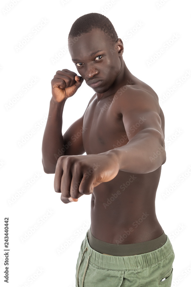 Young handsome buff Sudanese man naked torso in khaki trousers in boxing  punching stance piercing eye contact in portrait with copy space. A  metaphor for strength, agility and fighting sexual virility foto