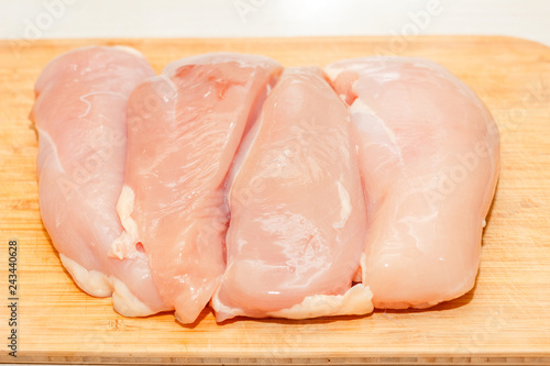 Raw skinless chicken breast fillets on a cutting board