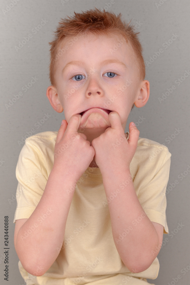 Fiery redhead young boy fingers in his mouth pulling lips down in sad face concept wearing a yellow shirt in portrait format with copy space. Meme or poster of cute redhead cheeky sad, bad tempered. Fiery redhead young boy fingers in his mouth pulling lips down in sad face concept wearing a yellow shirt in portrait format with copy space. Meme or poster of cute redhead cheeky sad, bad tempered.