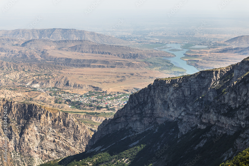 Caucasus mountains, desert valley, villages and river. Panoramic view from the edge of Sulak Canyon near Dubki village in sunny summer morning. Traveling in Dagestan Republic, Russia Caucasus mountains, desert valley, villages and river. Panoramic view from the edge of Sulak Canyon near Dubki village in sunny summer morning. Traveling in Dagestan Republic, Russia