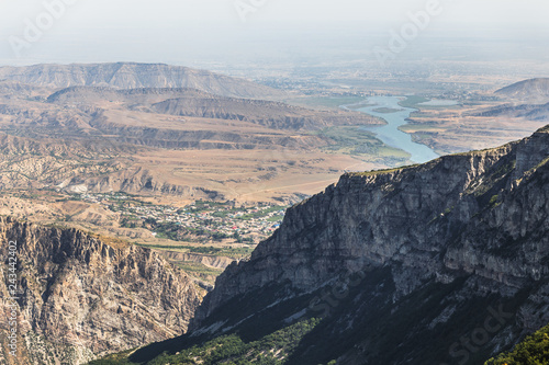 Caucasus mountains, desert valley, villages and river. Panoramic view from the edge of Sulak Canyon near Dubki village in sunny summer morning. Traveling in Dagestan Republic, Russia