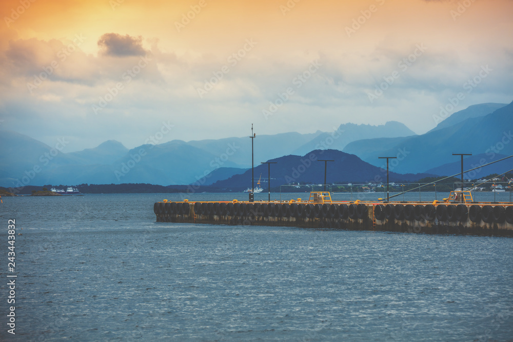 Bay in the evening light. Pier in the sea and mountains on the horizon. Alesund, Norway, Europe