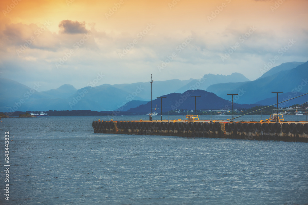 Bay in the evening light. Pier in the sea and mountains on the horizon. Alesund, Norway, Europe Bay in the evening light. Pier in the sea and mountains on the horizon. Alesund, Norway, Europe
