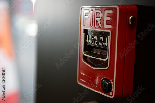 A red fire alarm box on a black wall