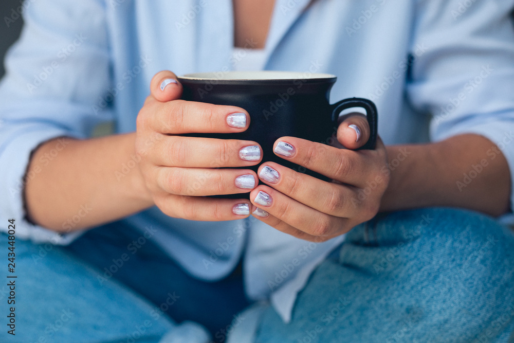 Cute girl with a beautiful manicure drinking coffee