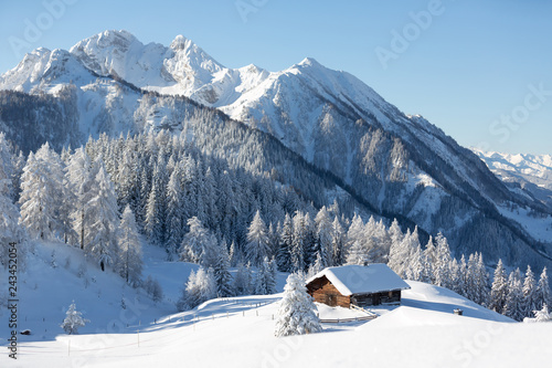 Winter onderland in Austrian Alps. Picturesque winter scene with traditional alpine hut and snowy forest