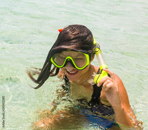Beach vacation fun woman wearing a snorkel scuba mask making a goofy face while swimming in ocean water. Closeup portrait of Asian girl on her travel holidays. Summer or winter destination.
