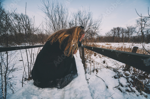 Depressed woman crying in park in winter.