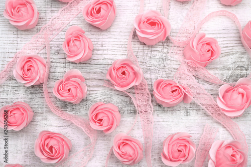 Pink roses with ribbon on wooden background