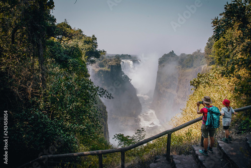 Konstfotografi Touristin mit Kind fotografiert die Victoria Falls am späten Nachmittag mit Rege