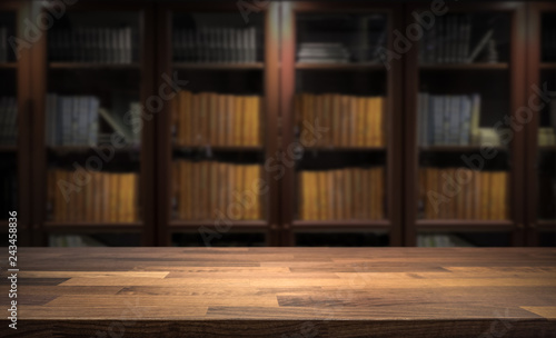 Blured bookshelf in small home library in the background. Table top for product display montage. Dark interior design.