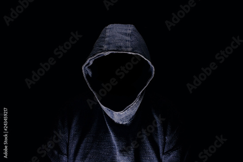 Mysterious man silhouette with darkened face, no visible face, in blue hoodie on dark background