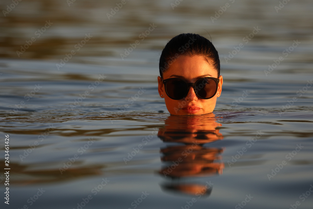 Brunette girl with glasses stuck her head out of water