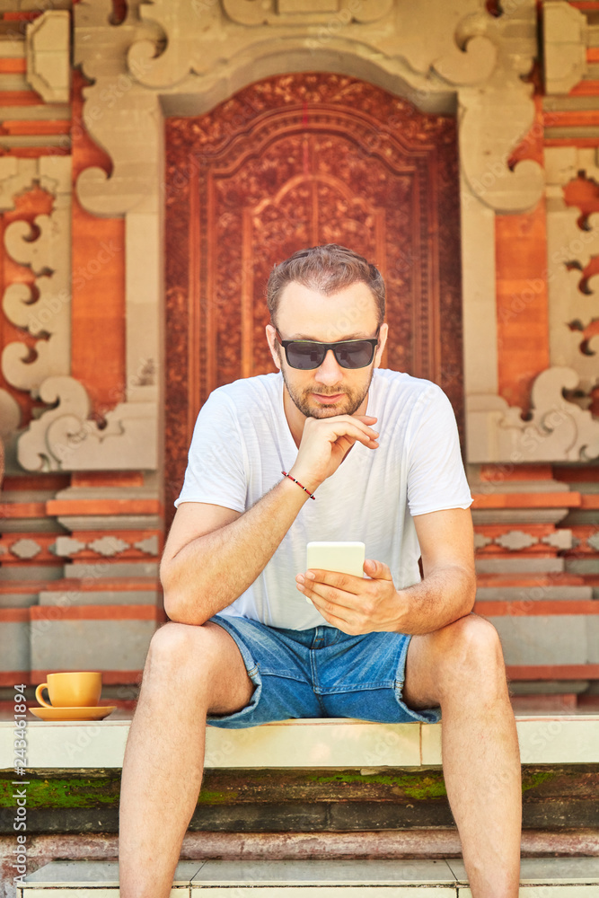 Man using cellpohne on the porch in front of a house. Man using cellpohne on the porch in front of a house.